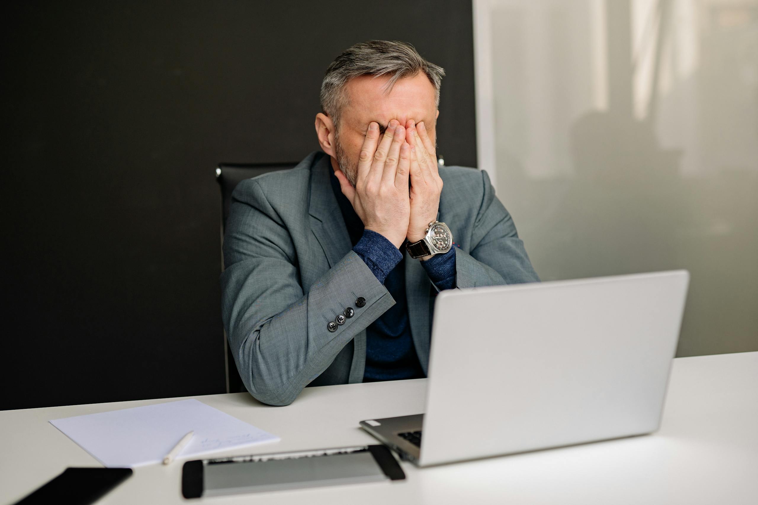 Businessman in gray suit showing frustration while working in office.